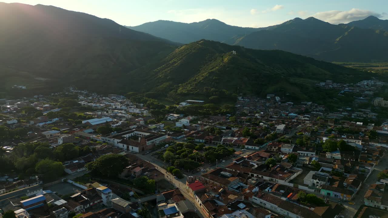 vista aérea estableciendo el parque de la ciudad de roldánillo al atardecer con tres colinas de cruces en la distancia