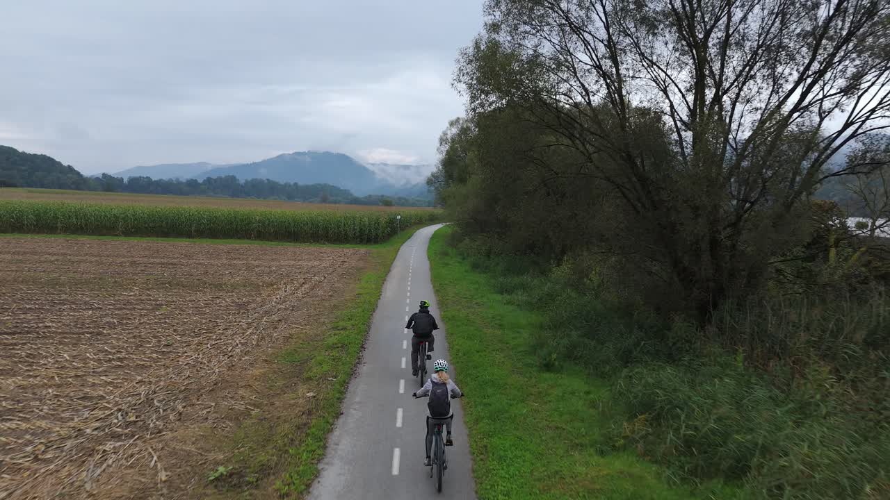 Couple Riding E-Bikes in the Countryside Along Drava River, Aerial