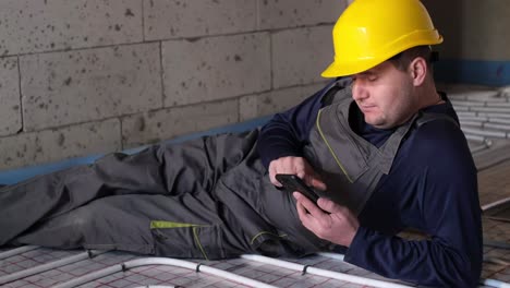 the plumber is resting after work the plumber is resting after work he is holding a smartphone in his hands professional plumber