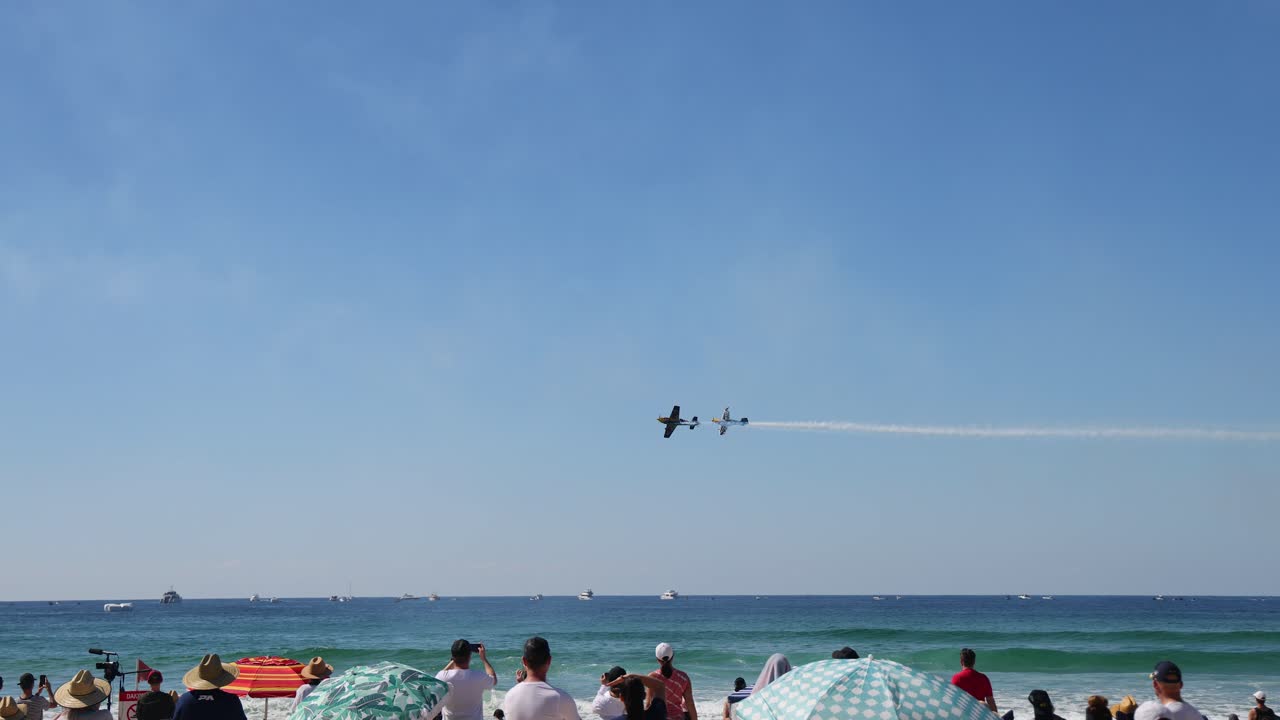 aviones realizan acrobacias sobre una escena de playa ocupada