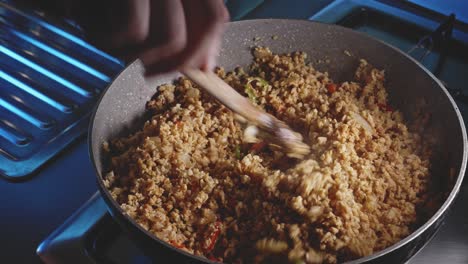 stirring together vegetables and soy in a frying pan with wooden spoon