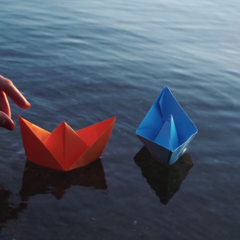 papieren schip in de hand van kinderen. blauw papieren schip. mooie zonsondergang.