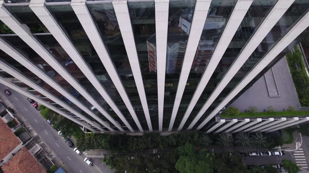 drone volando hacia arriba, cerca de un edificio con espejo simétrico, la cámara apuntando hacia abajo revelando el edificio a medida que sube