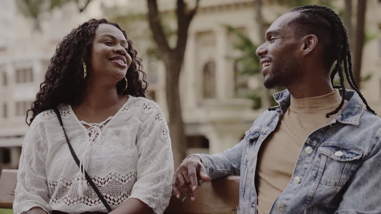 A Man and Woman Engaged in Happy Conversation on a Bench Outdoors