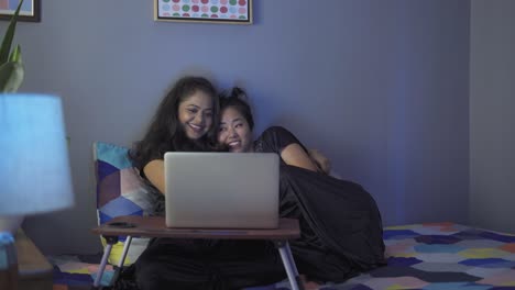 lgbt diverse multiethnic couple look at laptop screen sitting at home and discuss a movie or photography, lesbian homosexual female gay couple in love enjoying time together