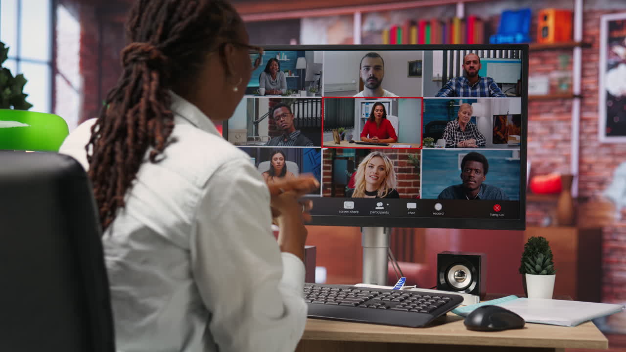 Employee greeting coworkers during videocall from home desk