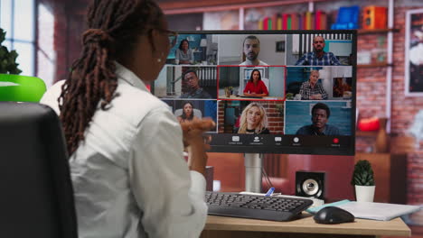 employee greeting coworkers during videocall from home desk