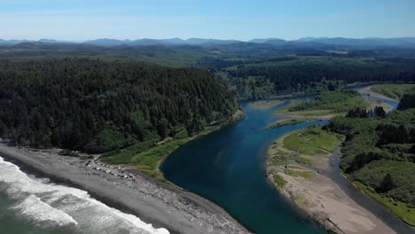 Aerial-cinematic-natural-landscape-of-Rialto-Beach-in-Washington,-drone-fly-above-coastal-green-tree-forest-and-pristine-Pacific-Ocean-water-during-sunny-day