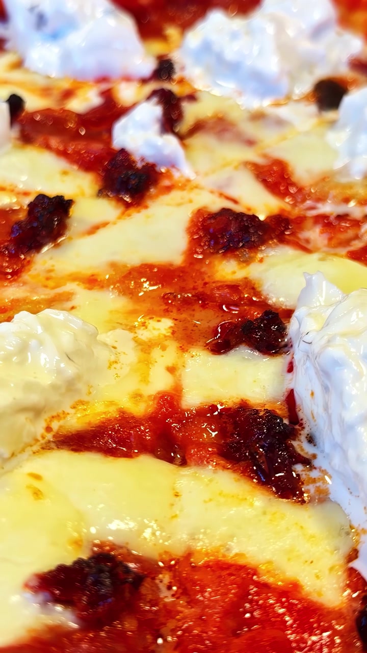 Primo piano estremo di una deliziosa pizza con mozzarella, salsa di pomodoro e burrata.