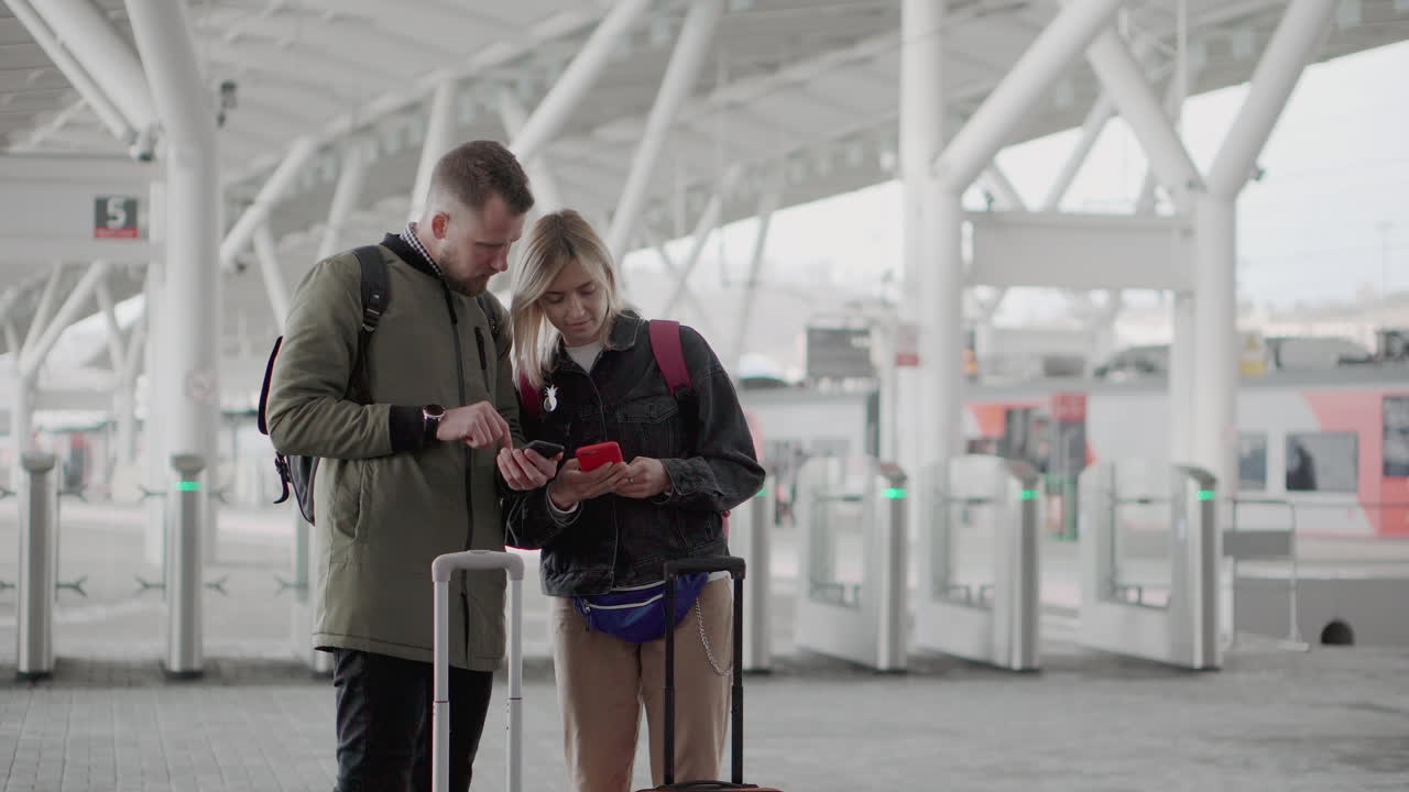pareja comprobando el teléfono en la estación de tren