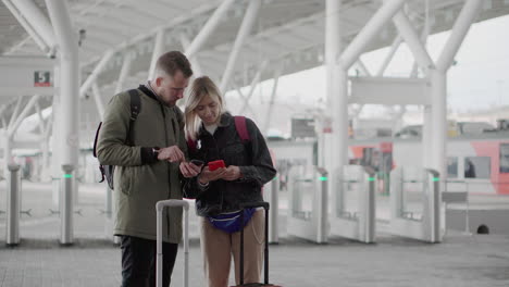 couple checking phone at train station