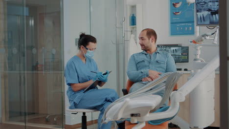 dental nurse taking notes and consulting patient with toothache