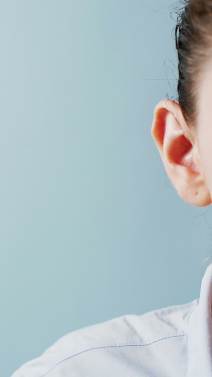 video vertical de la mano de una doctora caucásica detrás de su oreja de escucha, con espacio de copia