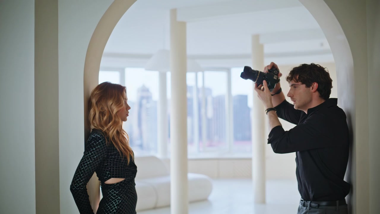 Modelo de moda posando con vestido negro de lentejuelas. Fotógrafo retratando a mujer en loft