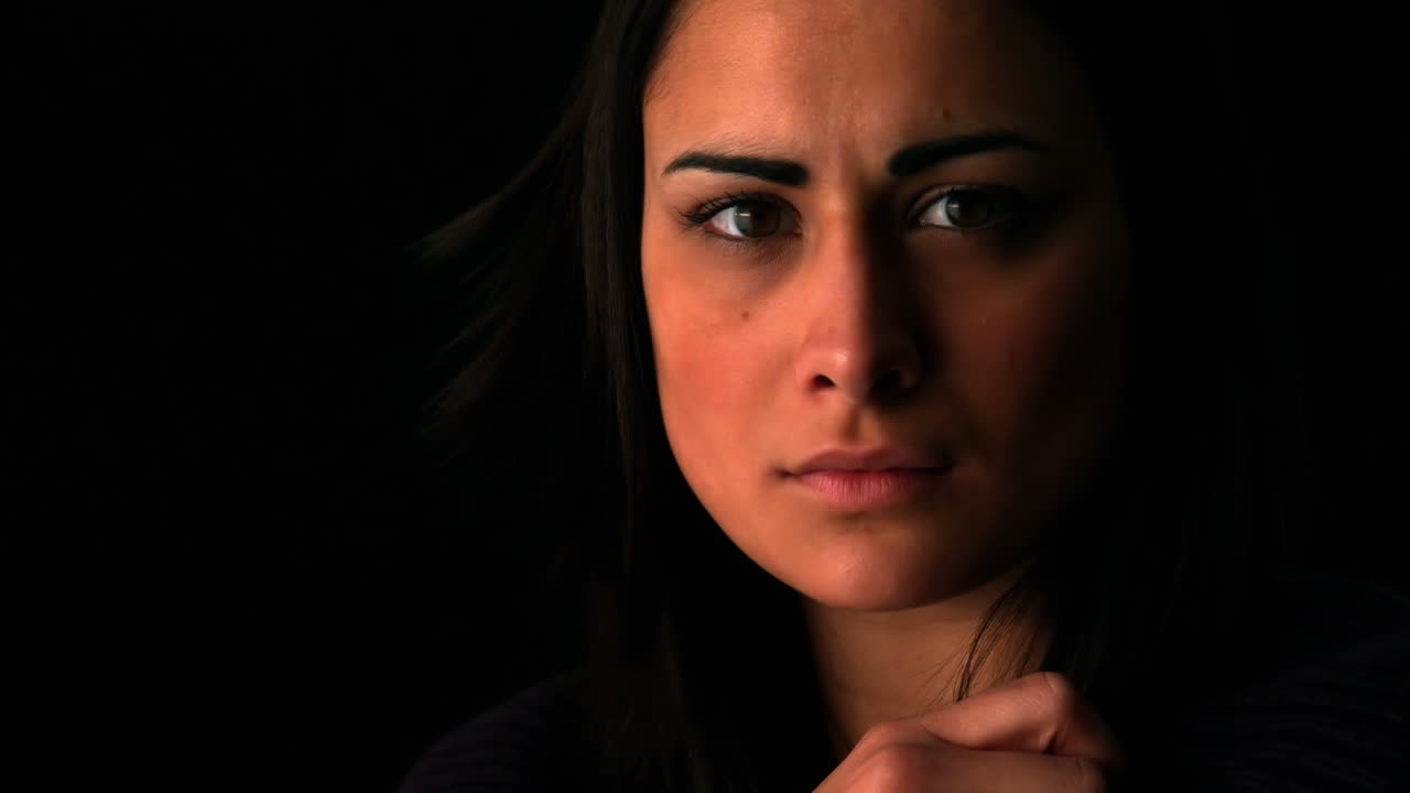 Upset brunette looking at camera on black background