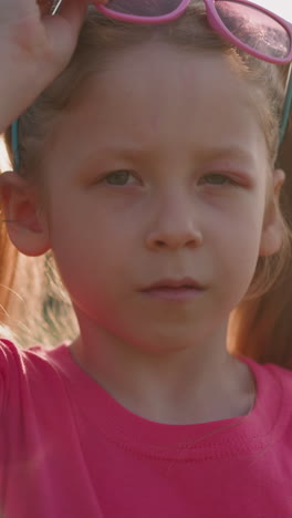 little girl with ponytails and swollen eyelid takes off sunglasses at countryside closeup slow motion. accident on playground. children fight