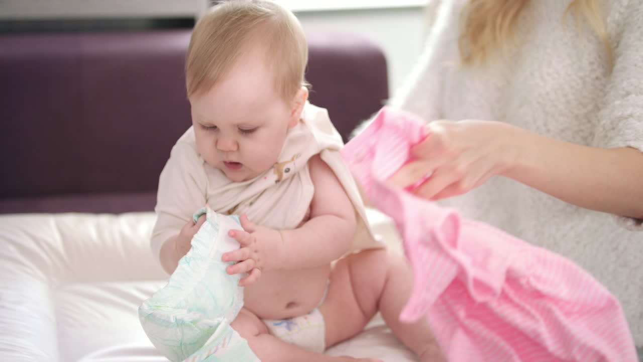 엄마는 아기에게 옷을 바 ⁇ 다. 귀여운 아기가 드레스를 입고