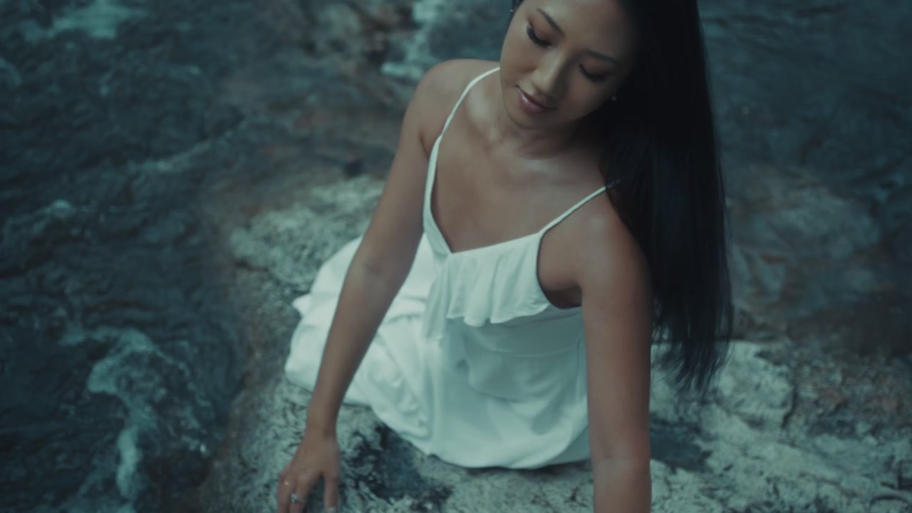 Young Woman in White Dress Sitting by a Flowing River