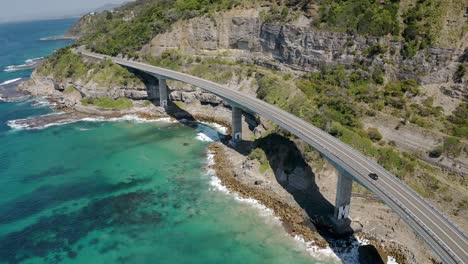 conduciendo a través de un puente de carretera que pasa por acantilados rocosos en el puente del acantilado marino cerca de wollongong, costa sur de nueva gales del sur, australia