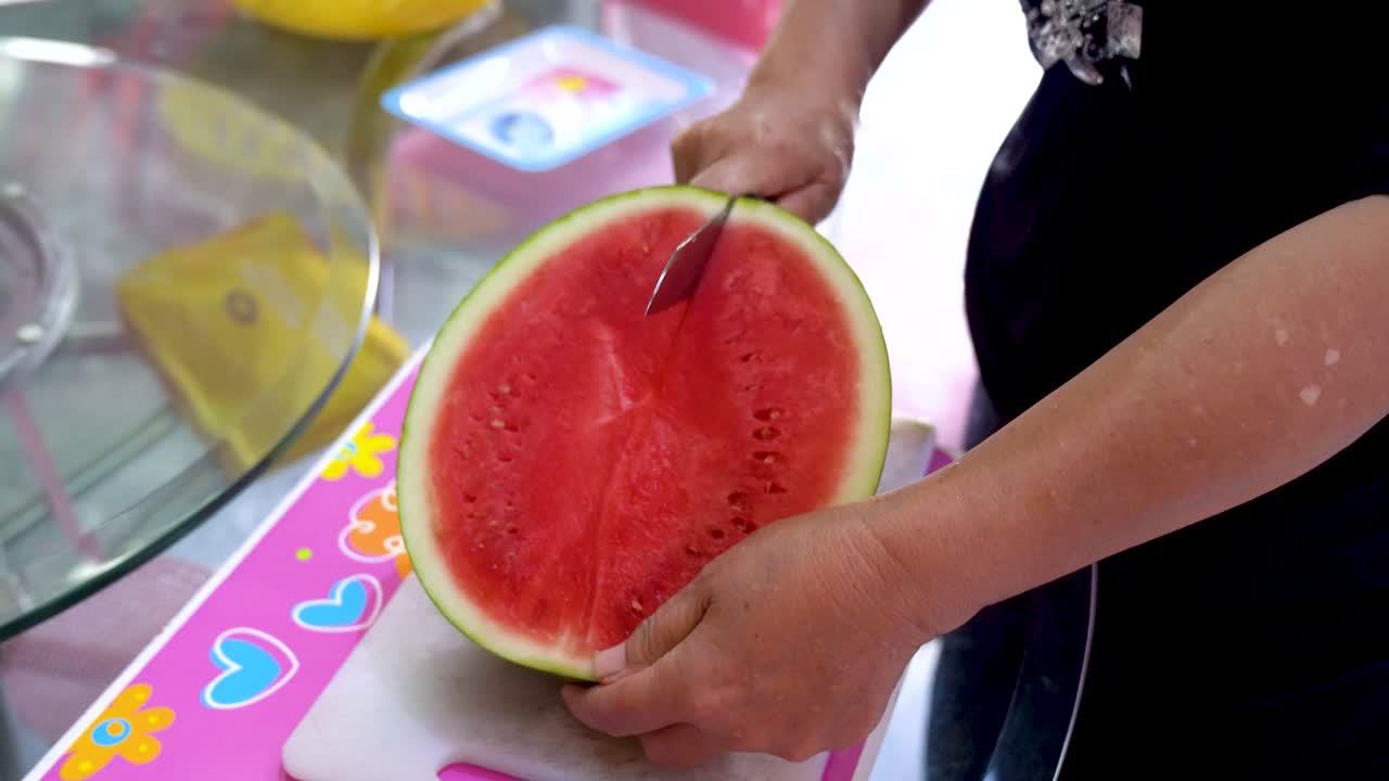 mujer cortando sandía en un cuarto en la cocina doméstica, vista cercana