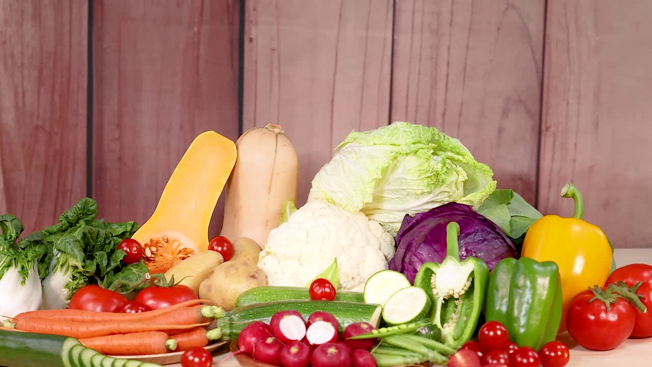 목조 배경 에 배열 된 신선 한 채소 의 활기찬 종류 는 다양한 색상 과 질감 을 보여 준다