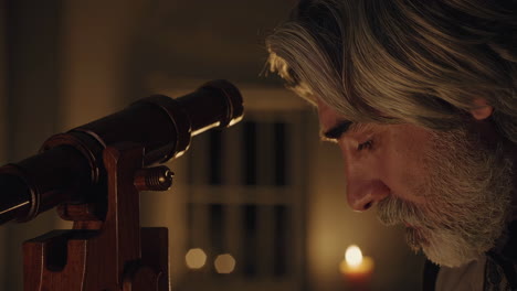 man observing through a telescope at night