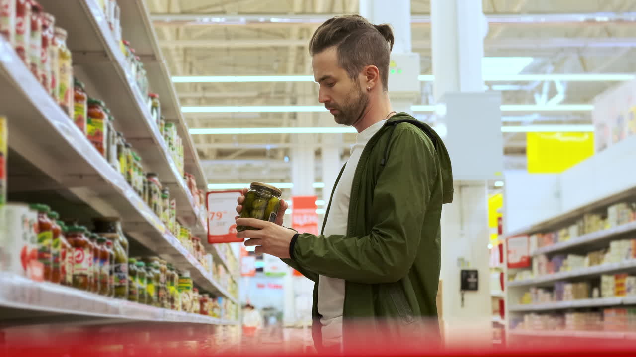 hombre comprando pepinillos en una tienda de comestibles
