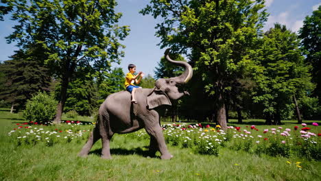 boy riding an elephant in a park