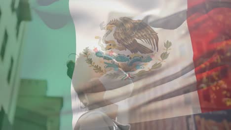 Animation-of-flag-of-mexico-waving-over-african-american-woman-wearing-face-mask-in-city-street