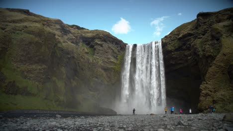 people at the base of large waterfall