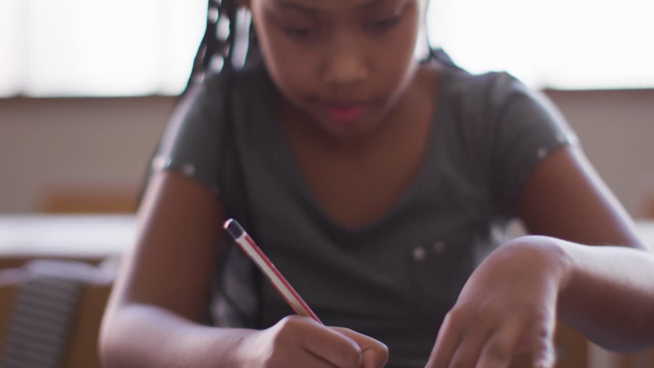 Girl drawing a line using a scale while sitting on her desk at school