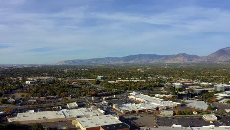 Left-trucking-aerial-drone-extreme-wide-landscape-shot-of-the-Salt-Lake-county-valley-covered-in-buildings,-busy-roads,-and-colorful-autumn-trees-on-a-warm-sunny-fall-evening-in-Utah