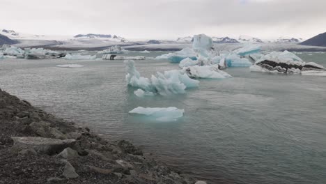 laguna glaciar en islandia con un hombre mirando y un video cardán caminando detrás