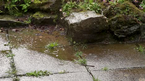 slow motion raindrops in puddle on stone patio