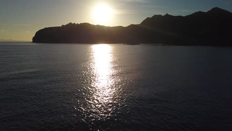 Sunset-Reflection-on-Ocean-Water-with-Dark-Silhouettes-of-Mountain---Aerial