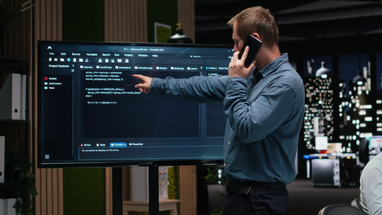 Software Developer Talking on Phone and Pointing at Code on Screen
