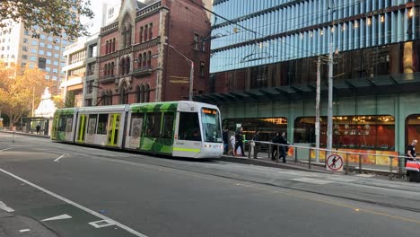 el tranvía pasa por delante de los edificios y los peatones.