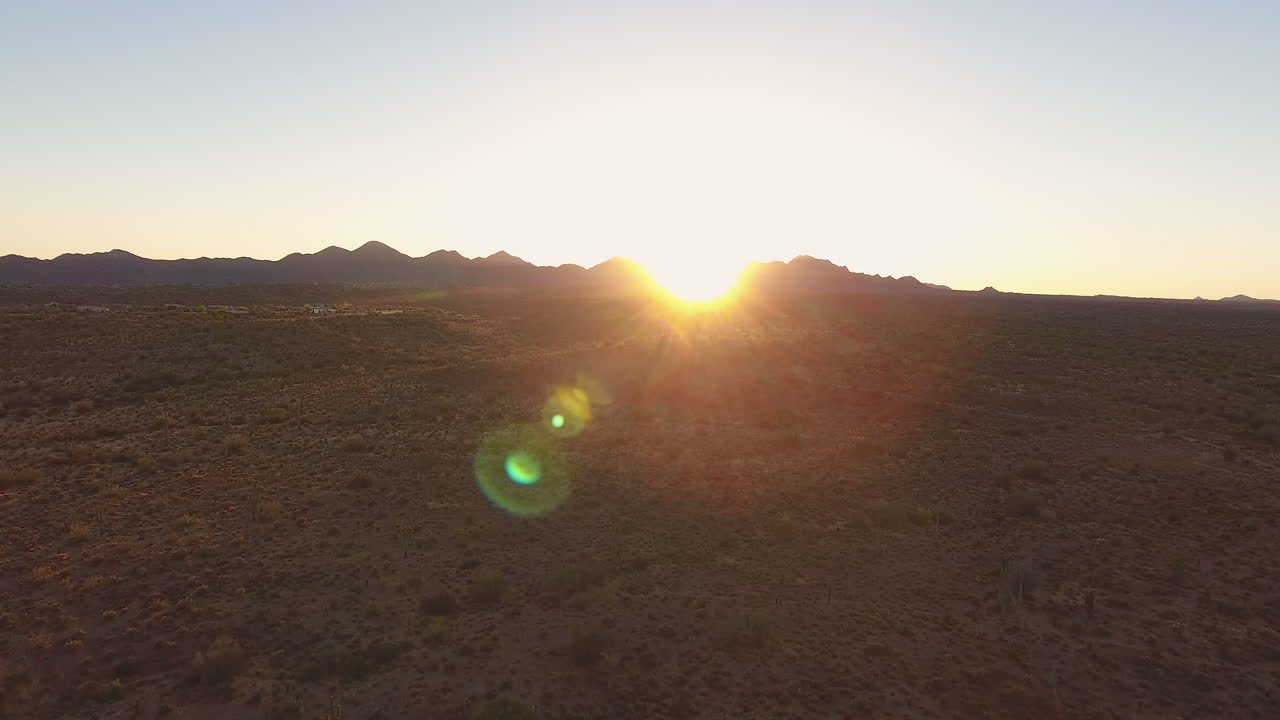 tiro de dron ascendente del desierto con puesta de sol detrás de la montaña en el fondo con destello de lente ubicado en flagstaff arizona
