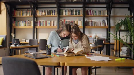 two teen girls study together in a library