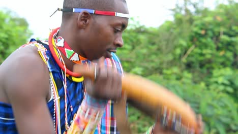 masai man shaking a traditional milk bottle and then drinking from it