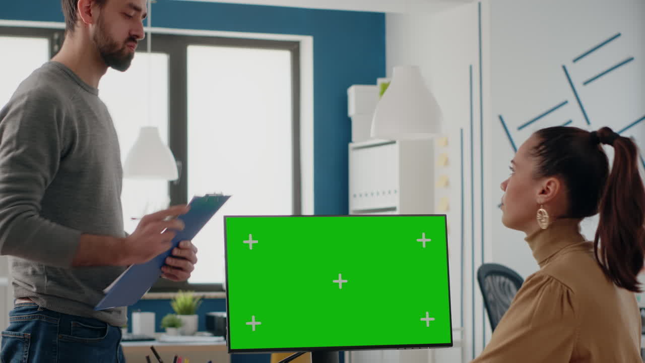 Workmates using computer with green screen on display