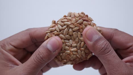 una mano sosteniendo y rompiendo una galleta de semilla de girasol