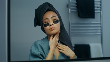 mujer aplicando parches oculares en el baño