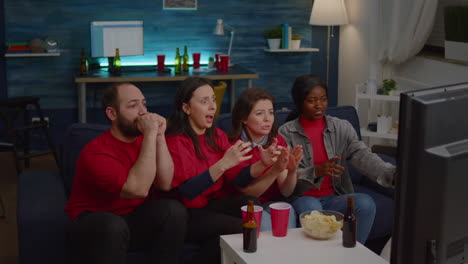 mixed race group of people watching at football game on television cheering sport team