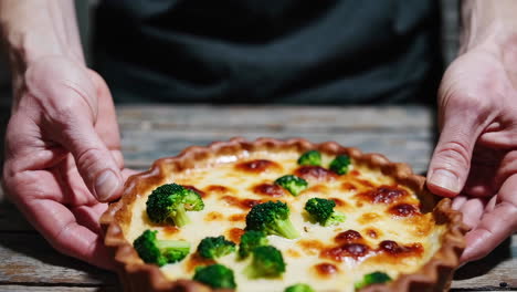 hands placing and lifting a homemade broccoli quiche