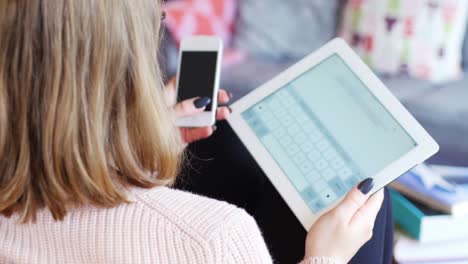 Frau-Benutzt-Digitales-Tablet-Und-Mobiltelefon-Im-Wohnzimmer