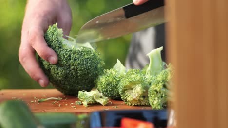 A-young-man-chops-a-broccoli-on-a-wooden-board-close-up