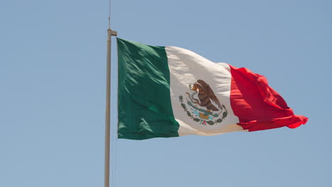 mexican flag in right of frame waving in the wind on bright sunny day