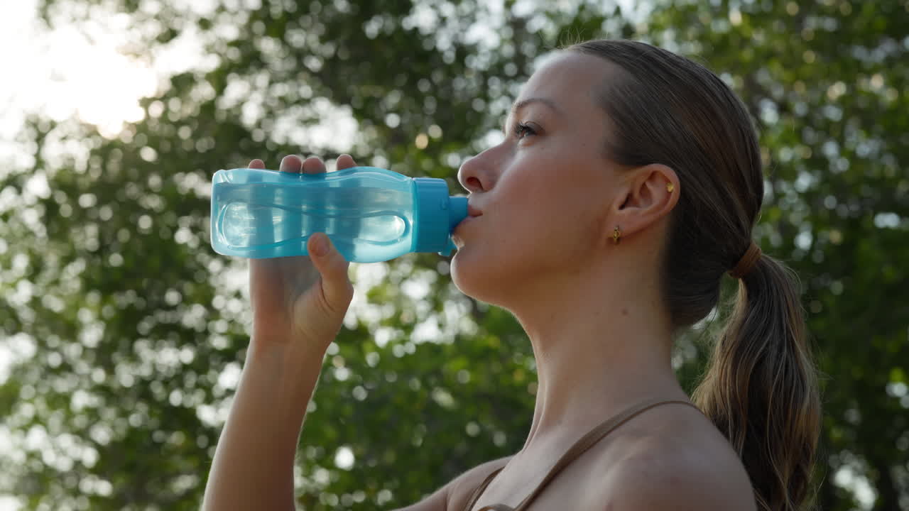 Mujer Joven Bebiendo Agua de una Botella al Aire Libre