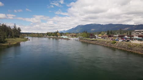 Aerial-View-Over-Waterway-River-Towards-Marina-at-Port-Alberni-Region-in-British-Columbia-Canada,-Waterfront-Landscape-and-Mountain-in-Horizon